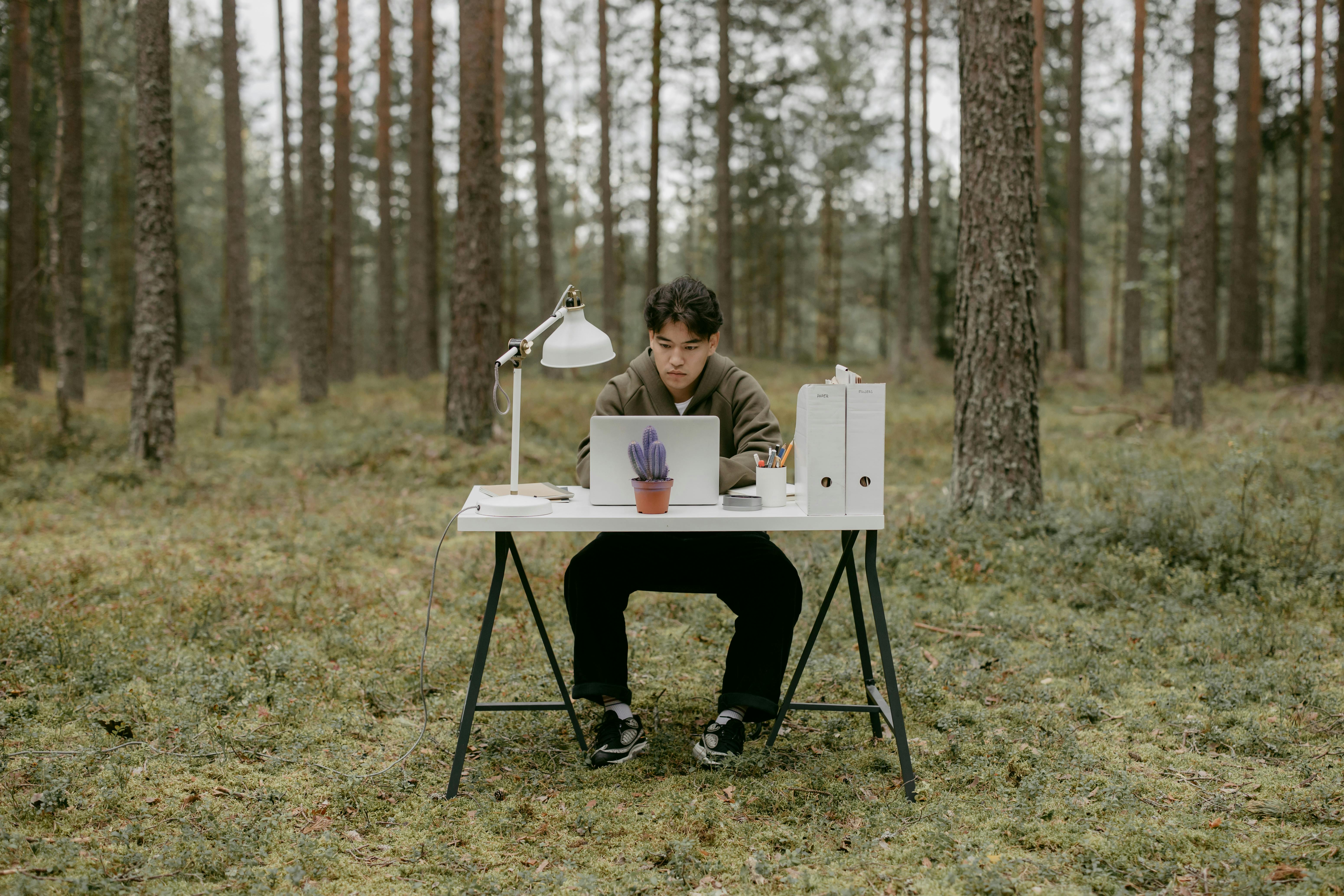 man-sitting-outside-with-laptop-in-middle-of-forrest